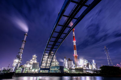 Low angle view of illuminated factory against sky at night