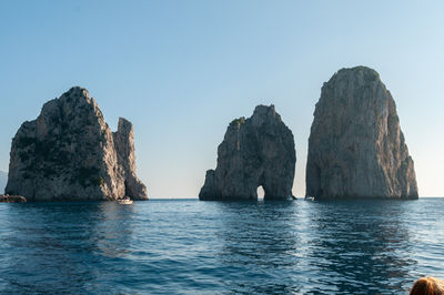 Rock formations in sea against clear sky