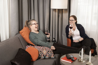 Female friends having wine in living room