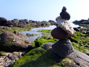 Stack of stones in sea against clear sky