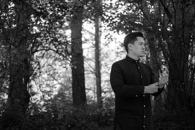 Thoughtful man in traditional clothing looking away while standing against trees