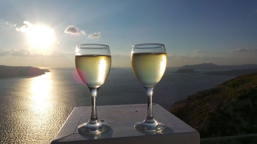 White wine served in glasses on table against sea