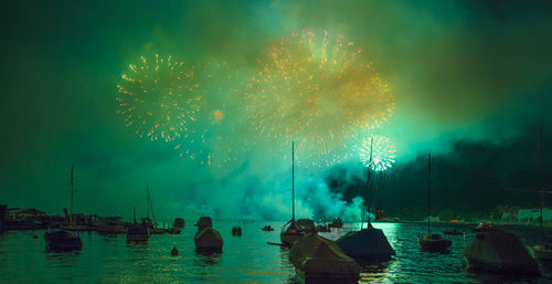 Firework display over lake against sky at night