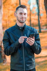 Young man smiling while standing during autumn