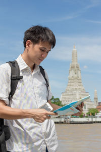 Young man using smart phone against sky