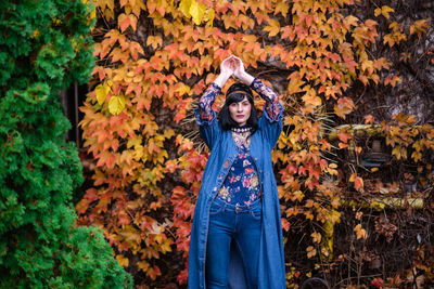 Portrait of young woman standing in autumn leaves