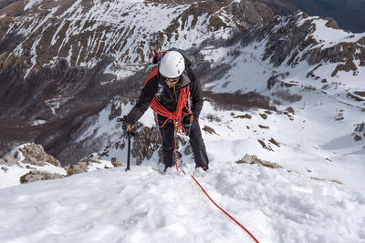 High angle view of man climbing snow covered mountain