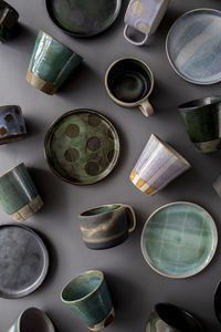 Ceramic cups, plates, and mugs on gray surface
