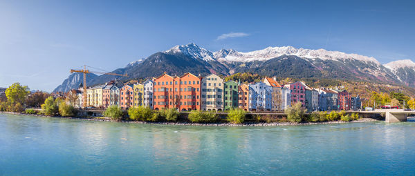 Buildings by mountains against blue sky