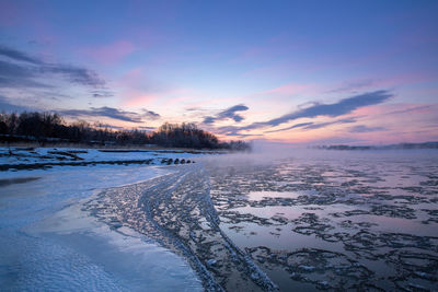 Scenic view of frozen lake against sky during sunrise