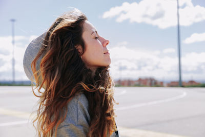Side view of smiling woman with eyes closed day dreaming on street