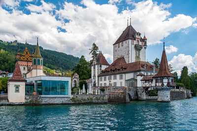 Buildings by river against sky