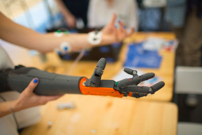 Close-up of woman holding robotic hand