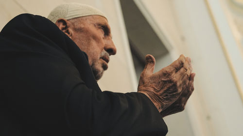 Old muslim man with a prayer cap praying to allah at mosque in ramadan month