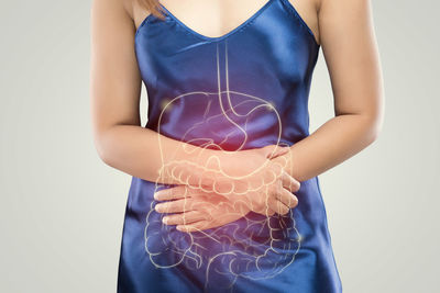 Midsection of woman holding hands against white background