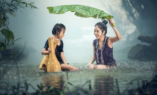 Full length of woman with arms raised in rain