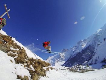 Low angle view of people skiing on snow covered mountain