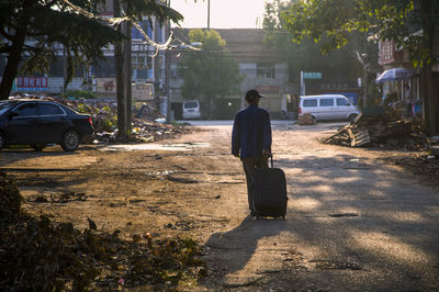 Rear view of man walking with luggage in town