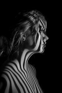 Side view of topless woman looking away over black background