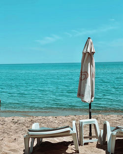 Chair on beach against sky