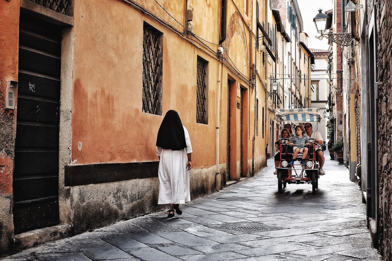 REAR VIEW OF MAN WALKING ON STREET