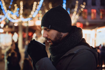 Rear view of man looking at illuminated street at night