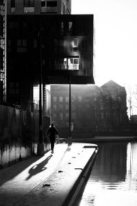 Silhouette man walking on street by buildings in city