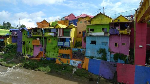 Multi colored houses by building against sky