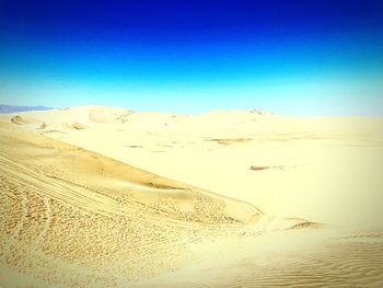 Scenic view of desert against clear blue sky