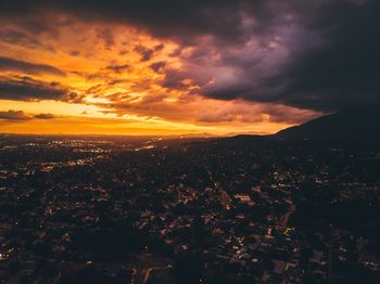 Scenic view of landscape against dramatic sky during sunset