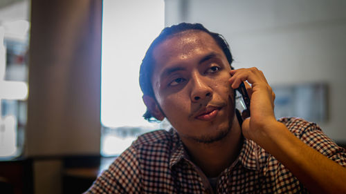 Portrait of young man holding smart phone at home