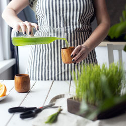 Woman pouring wheatgrass juice in cup 