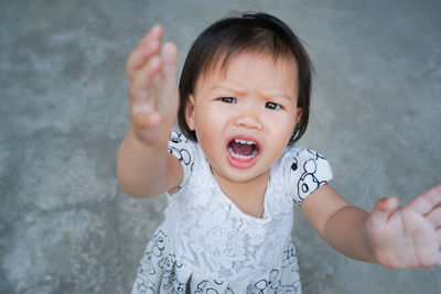 High angle portrait of angry baby girl gesturing while standing on footpath