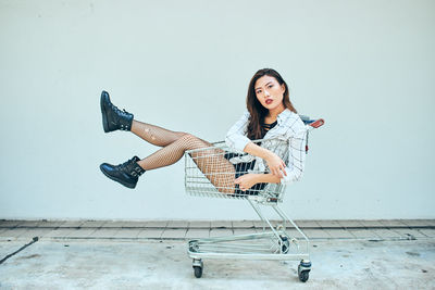 Side view portrait of beautiful young woman sitting in shopping cart