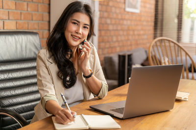 Young woman using phone while sitting on table