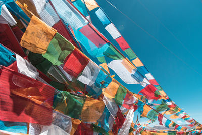 Low angle view of multi colored flags hanging against clear blue sky