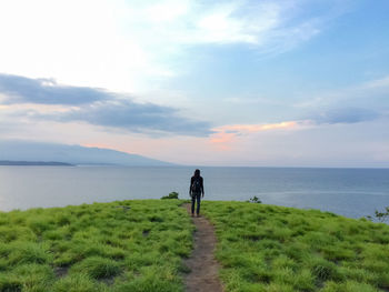 Rear view of man standing on shore against sky