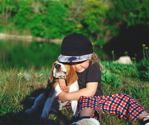 Low section of woman with dog sitting on grass