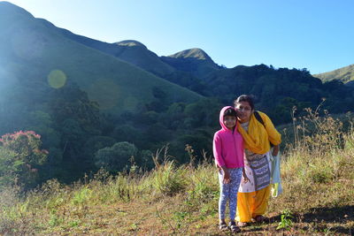 Young couple standing on mountain against clear sky