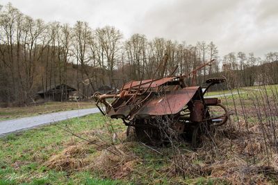 Abandoned cart on field against sky