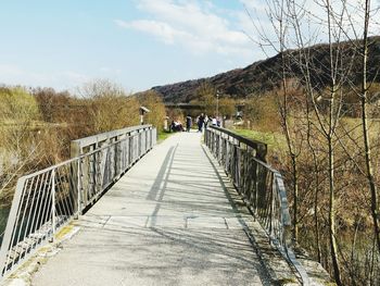 Footbridge amidst trees against sky