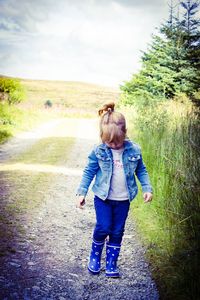 Rear view of siblings walking on grass against trees