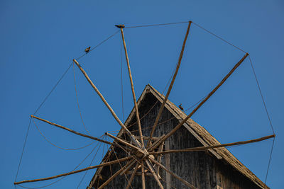 Low angle view of wooden mill against clear blue sky