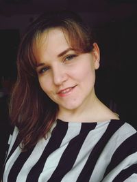 Portrait of smiling woman against black background