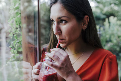 Close-up of woman having drink by window