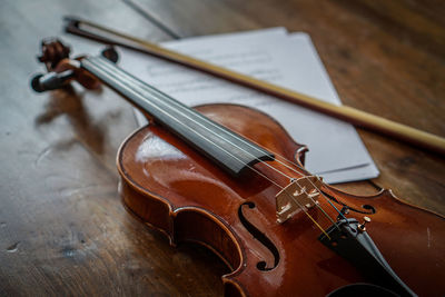 High angle view of violin with bow on wooden table