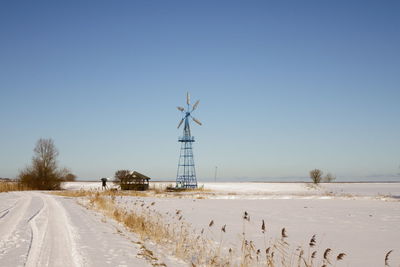 Snow covered land against clear sky during winter