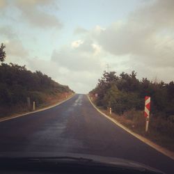 Country road against cloudy sky