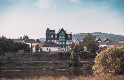 Buildings by river against sky