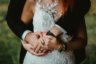 Midsection of bride and bridegroom holding hands